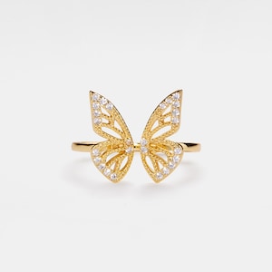 May include: A gold butterfly ring with clear cubic zirconia stones. The ring is delicate and features a detailed butterfly design.