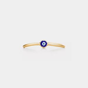 May include: A gold ring with a blue and white evil eye charm.