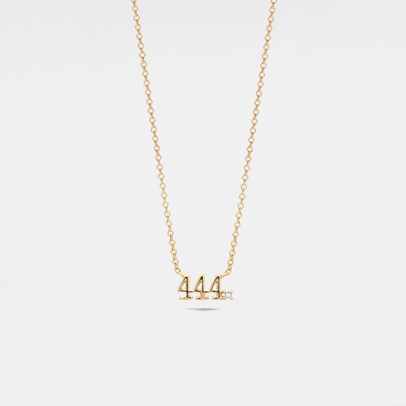 May include: A gold necklace with a pendant featuring the number 444 with a small diamond accent.