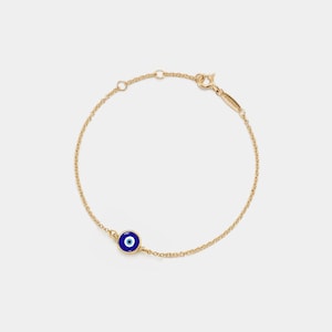 May include: A gold chain bracelet with a blue and white evil eye charm.