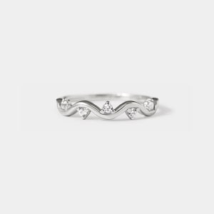 May include: A silver ring with a wavy band and five small clear stones.