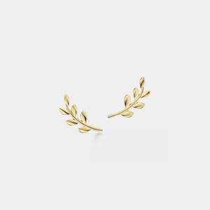 May include: A pair of gold-colored leaf-shaped earrings. Each earring features a delicate, curved stem with several small, oval-shaped leaves. The earrings are set against a plain white background, highlighting their intricate design and metallic sheen.