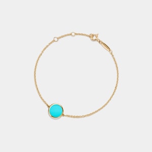 May include: A gold chain bracelet with a turquoise blue circle pendant.