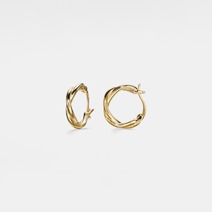 May include: A pair of gold-toned hoop earrings with a twisted design.