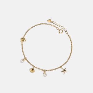 May include: A gold chain bracelet with a heart charm, a pearl charm, a seashell charm, a starfish charm, and a flower charm.