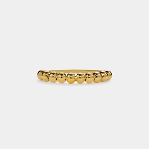 May include: A gold beaded ring with a simple design. The ring is made of a thin band with small, round beads.
