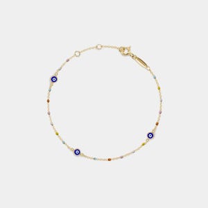 May include: A delicate gold bracelet with three blue evil eye charms and small, colourful beads. The bracelet has a fine chain and a secure clasp. A stylish piece of jewellery.
