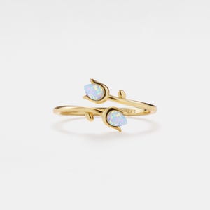 May include: A gold ring with two opal stones set in the shape of tulips. The ring is designed to be worn on the middle finger.