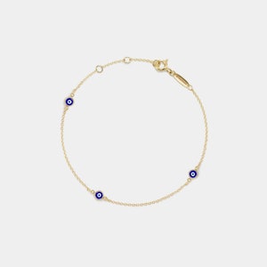 May include: A gold chain bracelet with three blue evil eye charms.