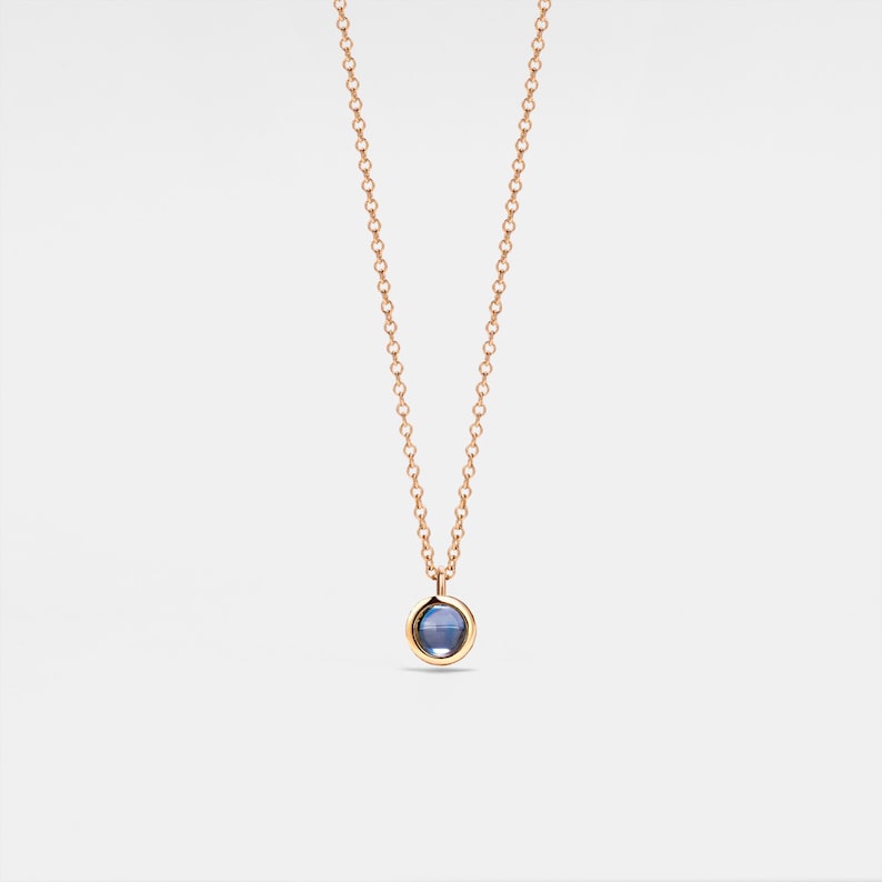 K&ouml;nnte beinhalten: Eine zarte goldene Kettenkette mit einem kleinen, runden blauen Edelstein-Anh&auml;nger.