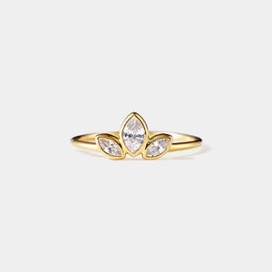 May include: A gold ring with three marquise-shaped clear stones set in a delicate floral design.