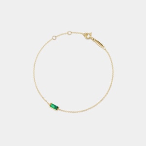Pode incluir: Um bracelete de corrente de ouro com uma única gema retangular verde esmeralda.