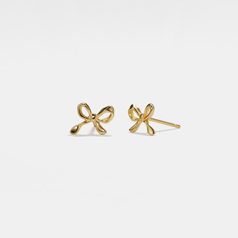 May include: A pair of gold bow-shaped stud earrings.