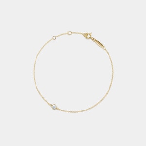 Può includere: Un delicato braccialetto a catena d'oro con un solo piccolo diamante rotondo.