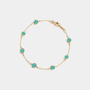 Op de afbeelding: Een delicate gouden armband met acht ronde, turquoise edelstenen. De edelstenen zijn gelijkmatig verdeeld over een fijne gouden ketting, met een veilige sluiting. De armband is ontworpen voor dagelijks gebruik en voegt elegantie toe.
