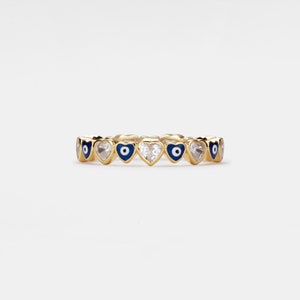 May include: Gold ring with a band of alternating heart-shaped charms and blue evil eye charms.