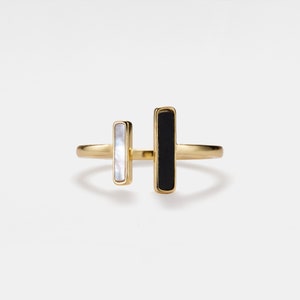 May include: A gold ring with two rectangular stones, one black and one white.
