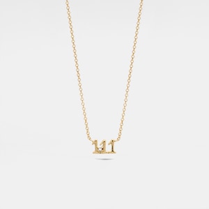 Könnte beinhalten: Eine goldene Kettenkette mit einem Anhänger, der die Zahl 111 mit einem kleinen Diamanten in der Mitte zeigt.