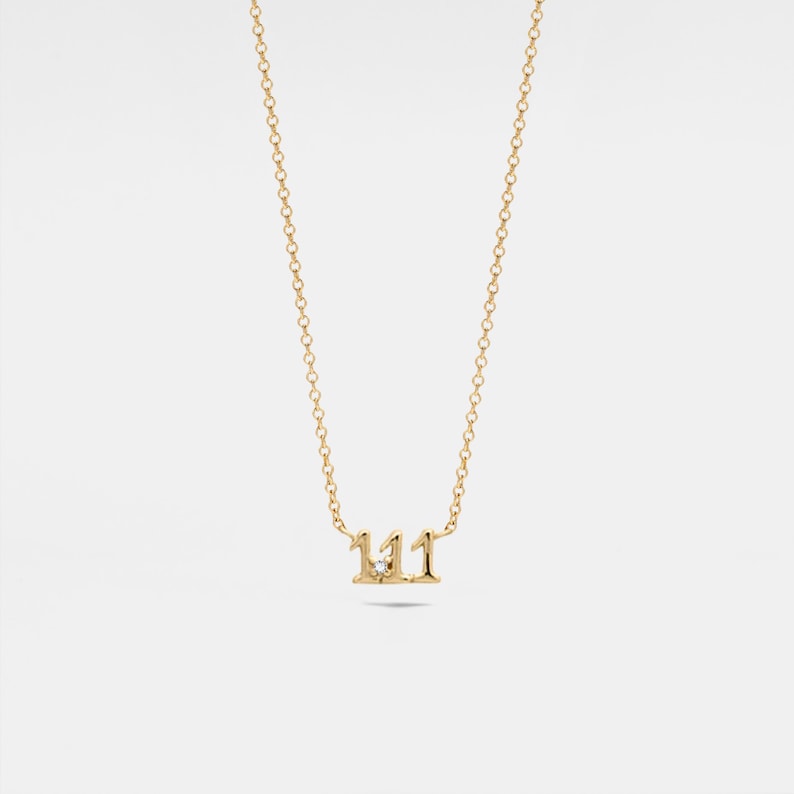 May include: A gold chain necklace with a pendant featuring the number 111 with a small diamond in the center.