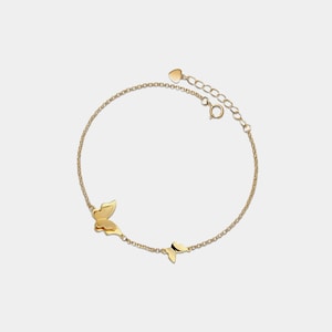 May include: A gold chain bracelet with two butterfly charms. The bracelet has a heart-shaped clasp.
