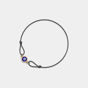 Puede incluir: Un brazalete de cordón gris oscuro con un dije de ojo turco dorado y azul.