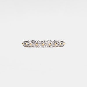 May include: A silver ring with a row of small daisy-shaped flowers with gold centers.