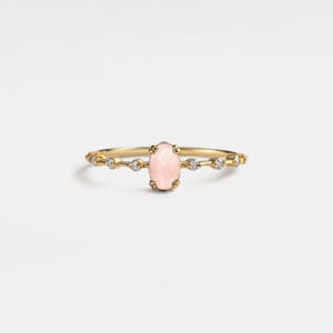 May include: A delicate gold ring with a pink oval gemstone and small clear stones set in a band.