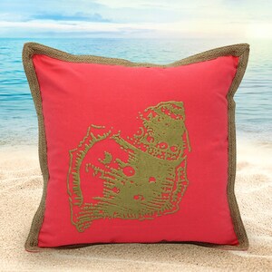 Może przedstawiać: Poduszka ozdobna w kolorze koralowym z obszyciem z juty, przedstawiająca haftowany wzór muszli w stonowanym odcieniu zieleni.