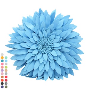 May include: A light blue decorative pillow shaped like a large flower. The pillow has multiple layers of petals, with a detailed center. The petals are a solid, soft blue color. The pillow is designed to resemble a dahlia or similar flower.