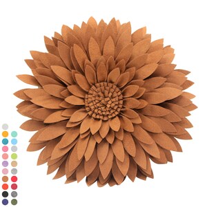 May include: A decorative, round pillow in the shape of a sunflower. The pillow is made of brown felt petals arranged in layers, with a textured center. The design resembles a large flower, suitable for home decor.