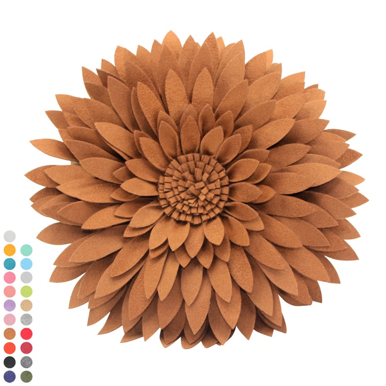 May include: A decorative, round pillow in the shape of a sunflower. The pillow is made of brown felt petals arranged in layers, with a textured center. The design resembles a large flower, suitable for home decor.