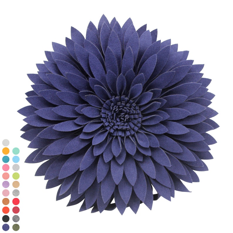 May include: A navy blue decorative pillow shaped like a large flower. The pillow has multiple layers of petals, creating a textured, floral design. The petals are arranged in a circular pattern, with a detailed center.