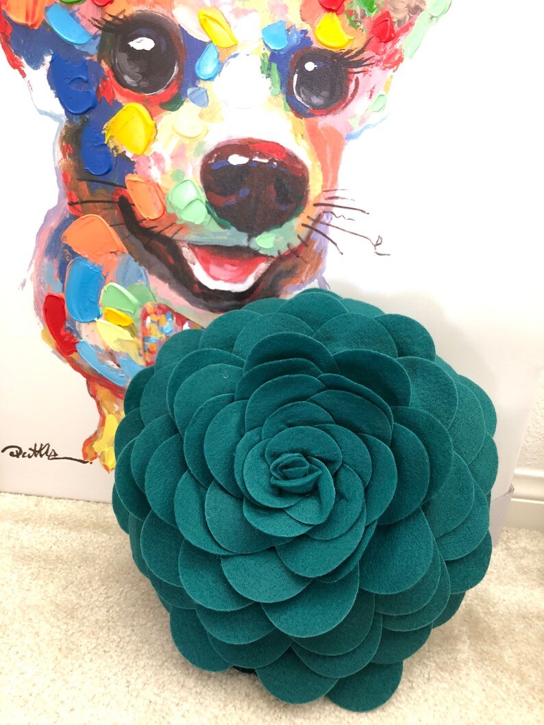 K&ouml;nnte beinhalten: Runder Kissen in Form einer Rosette aus blaugr&uuml;nem Filz mit 3D-Design.