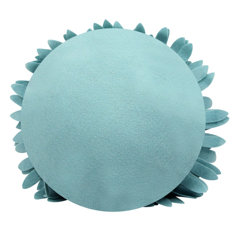May include: A round, light blue decorative pillow with a textured surface. The pillow is surrounded by a ring of petal-shaped accents, creating a floral or sunburst design. The overall aesthetic is soft and inviting.