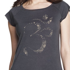 May include: A charcoal gray t-shirt with a gold Om symbol design. The symbol is made up of a series of circles and lines, creating a celestial pattern.