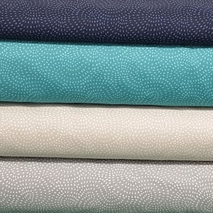 May include: Four fabric swatches with a white dot pattern on a blue, teal, beige, and grey background. The fabric is folded in a stack.