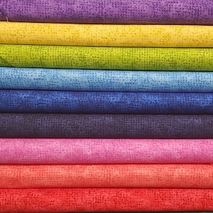 May include: A stack of ten fabric swatches in various colours, each with a subtle speckled pattern. The colours are purple, yellow, green, light blue, blue, dark blue, pink, orange, and red.