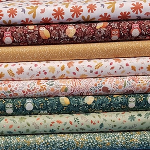 May include: A selection of patterned fabrics stacked on top of each other. The fabrics display designs of owls, leaves, and floral patterns in shades of brown, green, yellow, and white. These fabrics are likely cotton or a similar material, ideal for crafting.