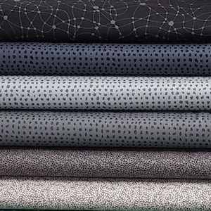May include: A stack of six fabric swatches in various shades of gray with different patterns. The top swatch has a black and gray geometric pattern, the second swatch has a gray and white polka dot pattern, the third swatch has a gray and white speckled pattern, the fourth swatch has a gray and white speckled pattern, the fifth swatch has a gray and white floral pattern, and the bottom swatch has a gray and white coral pattern.