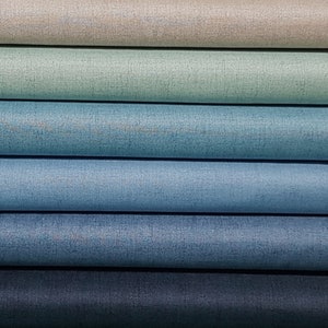 May include: A stack of six fabric swatches in shades of blue, green, and beige. The swatches are arranged in a gradient from light to dark.