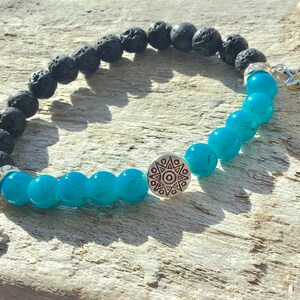 May include: A bracelet with black lava rock and turquoise beads, accented with silver charms of a crescent moon and a star.