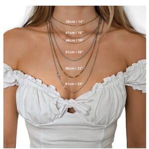 May include: A model wears a variety of silver and gold chain necklaces, each with a different length. The lengths are labeled in inches and centimeters: 14 inches/36 cm, 16 inches/41 cm, 18 inches/46 cm, 20 inches/51 cm, 22 inches/56 cm, and 24 inches/61 cm.