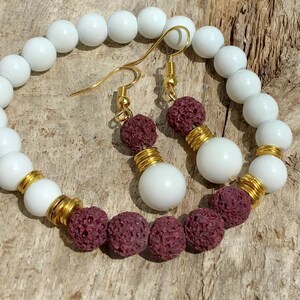 May include: A white beaded bracelet with gold spacers and matching earrings with burgundy lava rock beads.