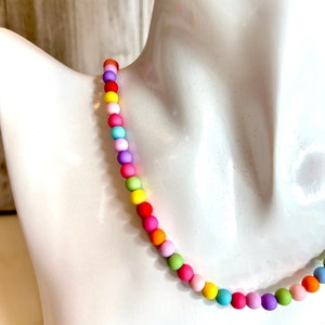 May include: A colorful beaded necklace with a rainbow of colors, including pink, yellow, green, blue, and orange.