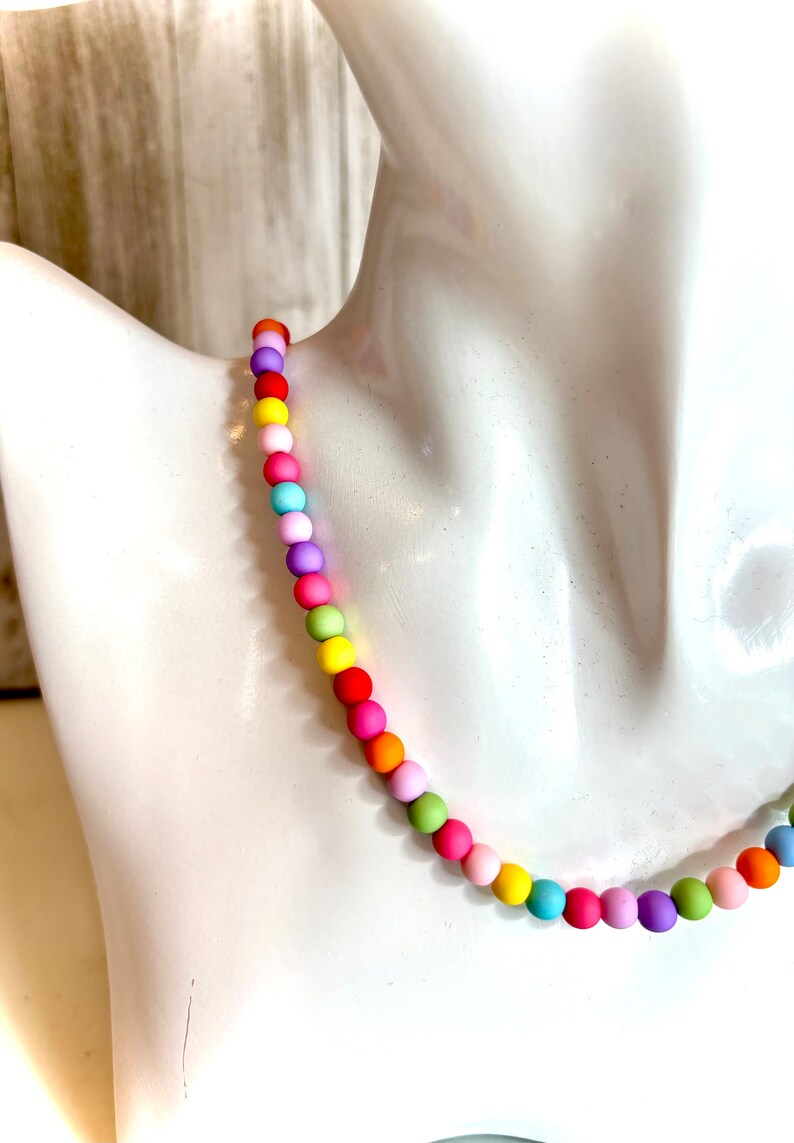May include: A colorful beaded necklace with a rainbow of colors, including pink, yellow, green, blue, and orange.