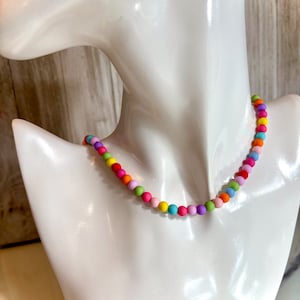 May include: A colorful beaded necklace with alternating pastel colors, including pink, purple, yellow, green, and orange.