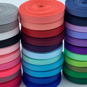 May include: A collection of 20 spools of ribbon in various colors, including red, blue, green, purple, pink, and white. The ribbon is arranged in stacks, with each stack containing a different color. The ribbon is all the same width and has a ribbed texture.