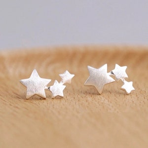 May include: Two silver star stud earrings. Each earring has four small stars in a cluster design.