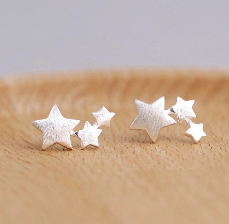 May include: Two silver star stud earrings. Each earring has four small stars in a cluster design.