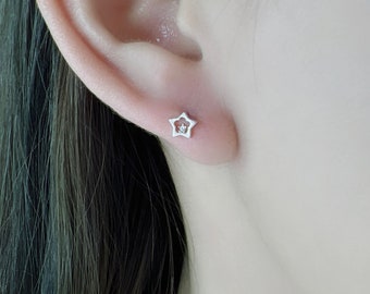 Può includere: Un orecchino a forma di stella in argento con un piccolo ciottolo trasparente al centro.